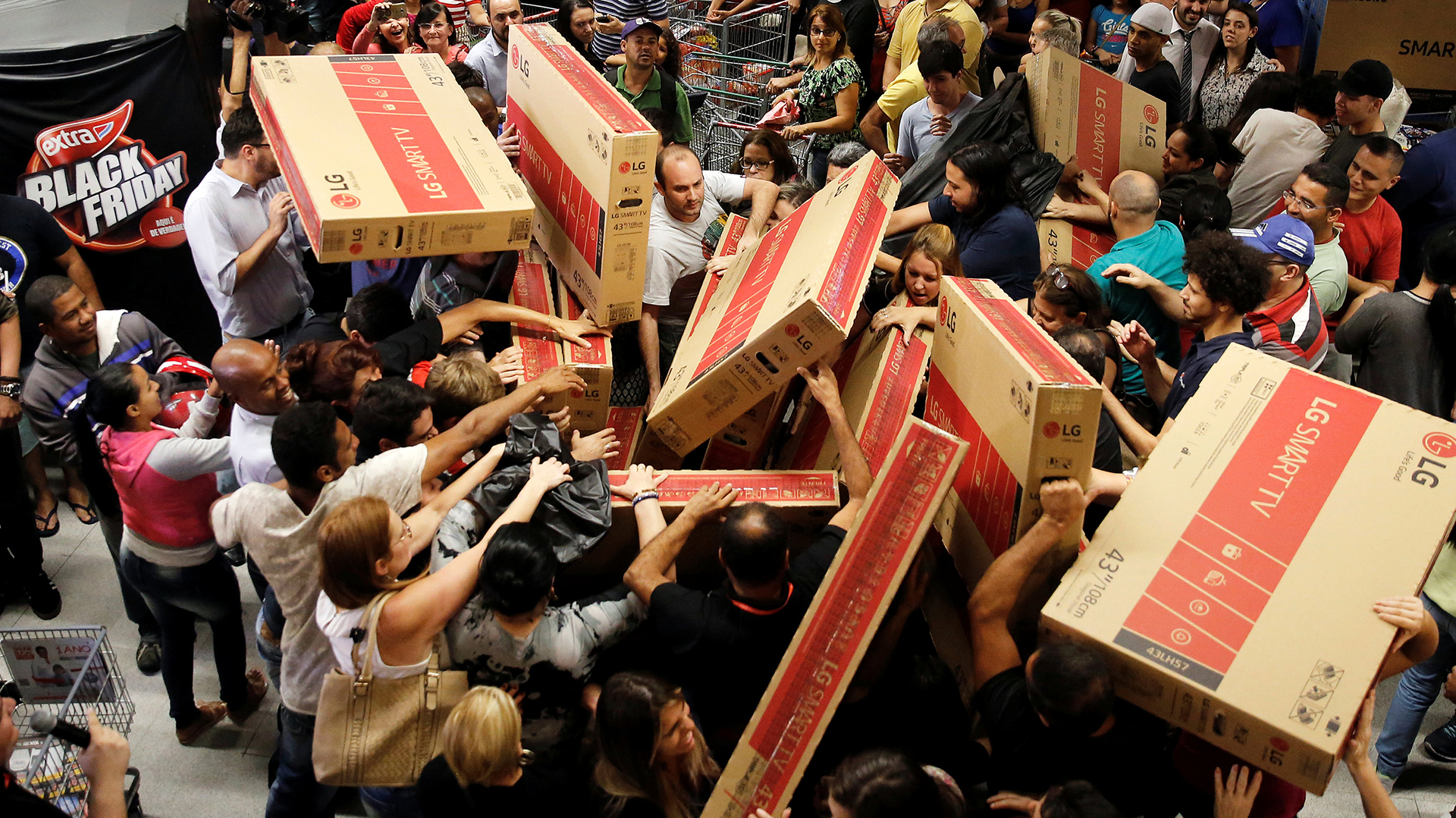 Shoppers reach for television sets as they compete to purchase retail items on Black Friday at a store in Sao Paulo